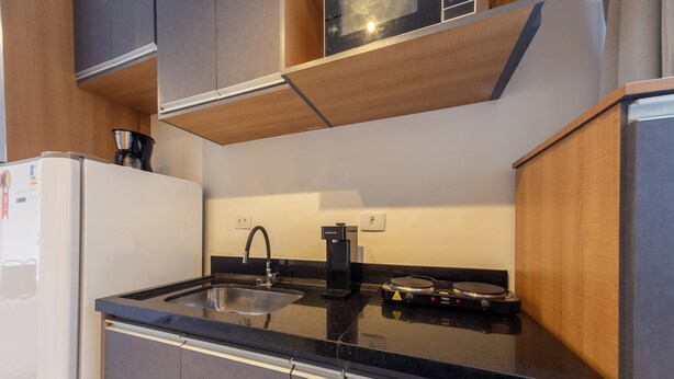 A modern kitchen with a black countertop, stainless steel sink, and a coffee machine.