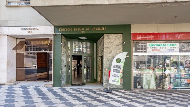 L’entrée d’un immeuble, avec une enseigne indiquant « Edificio Barão de Jaguaré », et un magasin situé à proximité appelé « Germinal Sebo ».
