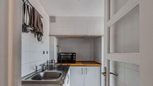 A kitchen with white cabinets, a microwave, a sink, and a wooden countertop.
