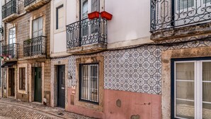 A building with multiple balconies, a patterned wall, and a cobblestone street.