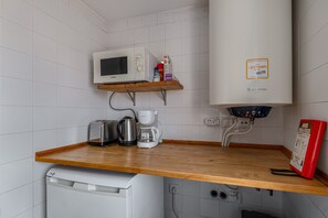 A kitchen with a microwave, coffee maker, toaster, kettle, and a dishwasher.