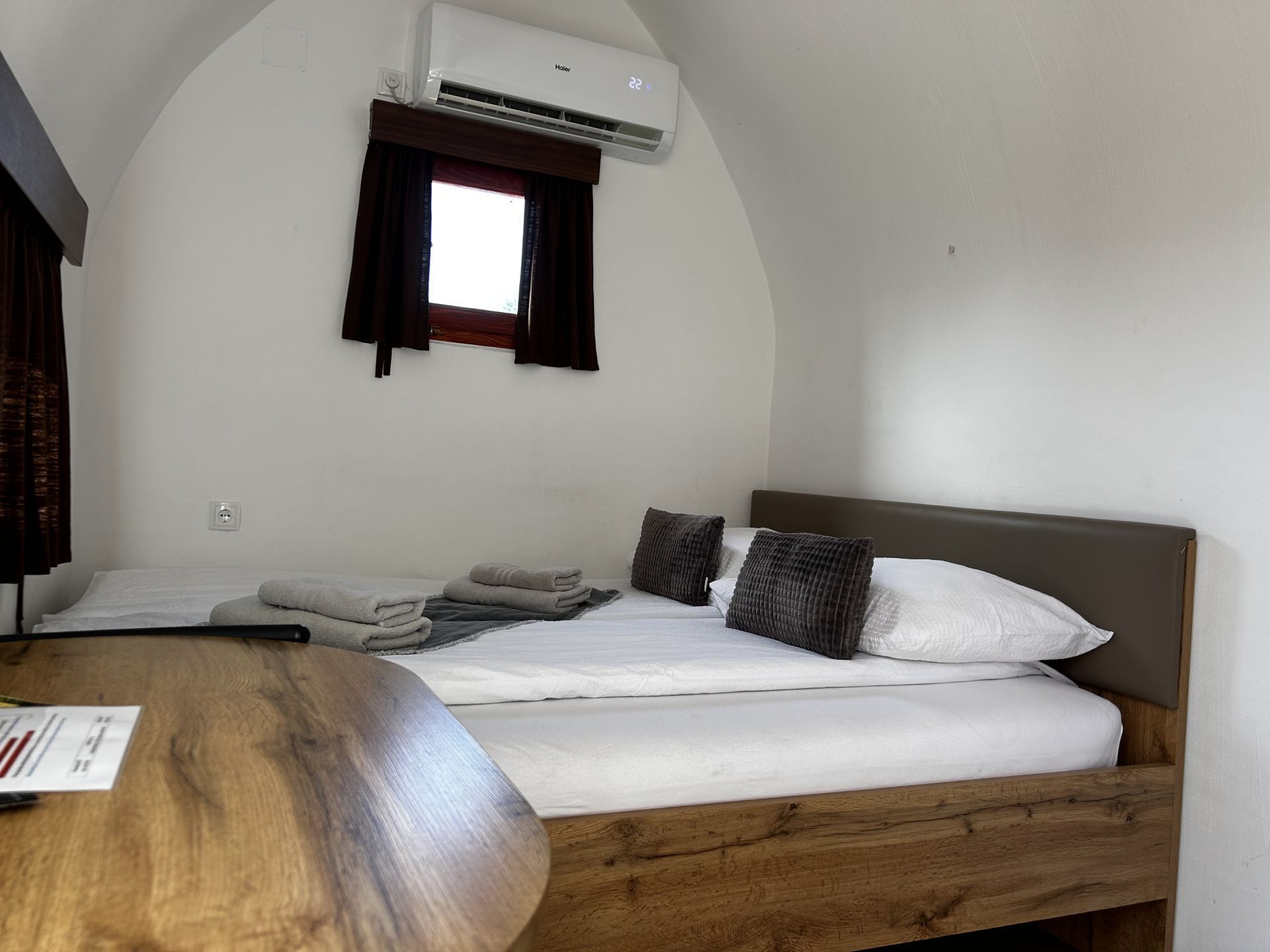 Une chambre avec un lit, une table en bois et un appareil de climatisation.