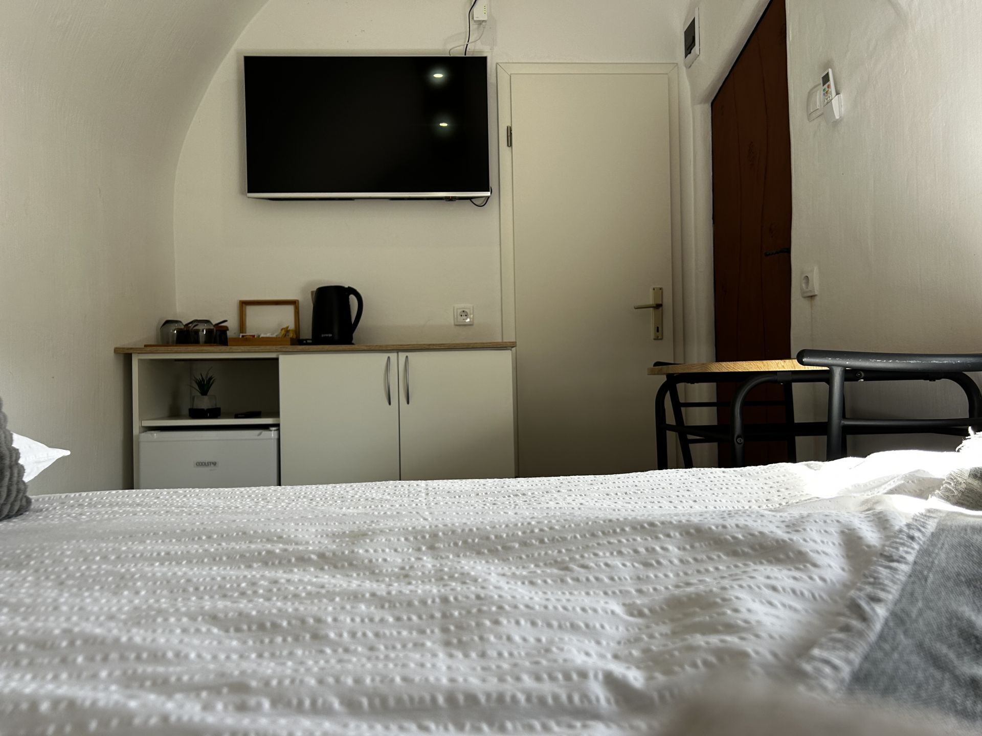 A bedroom with a bed, a desk, a television, and a wardrobe.