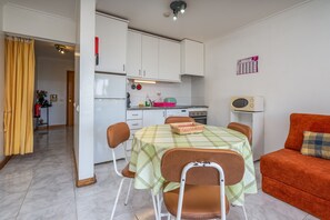 Ein kompakter Wohnbereich mit Essplatz, Küchenzeile und einer Couch.