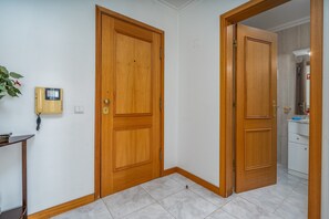 Una habitación con dos puertas de madera, un teléfono y una pequeña mesa con una planta.
