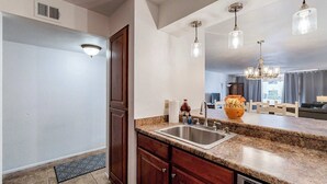 A kitchen with granite countertops, a stainless steel sink, wooden cabinets, and pendant lighting. - Scottsdale Getaway (Scottsdale)