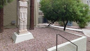 A stone monument with intricate carvings, a tree, and a building in the background. - Scottsdale Getaway (Scottsdale)