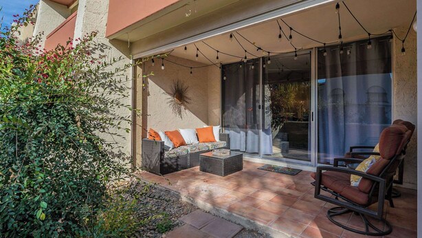 An outdoor patio with a sofa, a chair, and a table. There is a glass door leading to a balcony. - Scottsdale Getaway (Scottsdale)