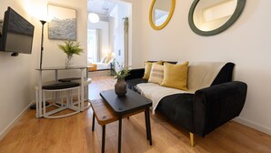 Un salon moderne avec un canapé noir, une petite table sur laquelle est posé un vase, et deux miroirs fixés au mur.