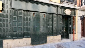 Une façade d’immeuble avec de grandes portes vertes, un couvercle de regard d’égout et une enseigne au-dessus de la porte.