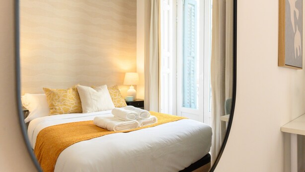Une chambre d’hôtel avec un lit, une table de chevet, une lampe et une fenêtre.
