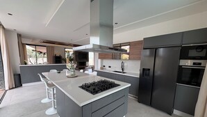 A modern kitchen with a central island, built-in appliances, and a large window. - New 480 m² villa with service 10 mn from center (Marrakech)