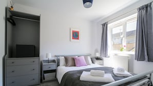 A modern hotel room with a bed, bedside tables, a wardrobe, and a window with curtains. - This beautifully presented home offers a comfortable and relaxing getaway (Bodmin)
