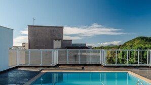 Una piscina en la azotea con vistas despejadas a una montaña y un edificio al fondo.