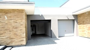 A modern building with a garage door, a covered entrance, and a metal staircase. - New, large holiday home for 10 people (Kołczewo)