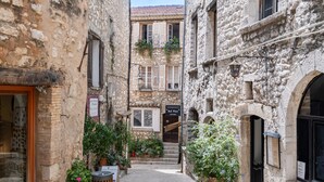 Une rue étroite bordée d’immeubles en pierre, avec une devanture de magasin bien visible et un escalier menant à l’étage supérieur.