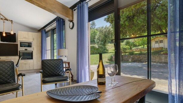 Una cocina moderna con electrodomésticos integrados, un comedor con mesa y sillas de madera, y un ventanal con vistas al exterior.
