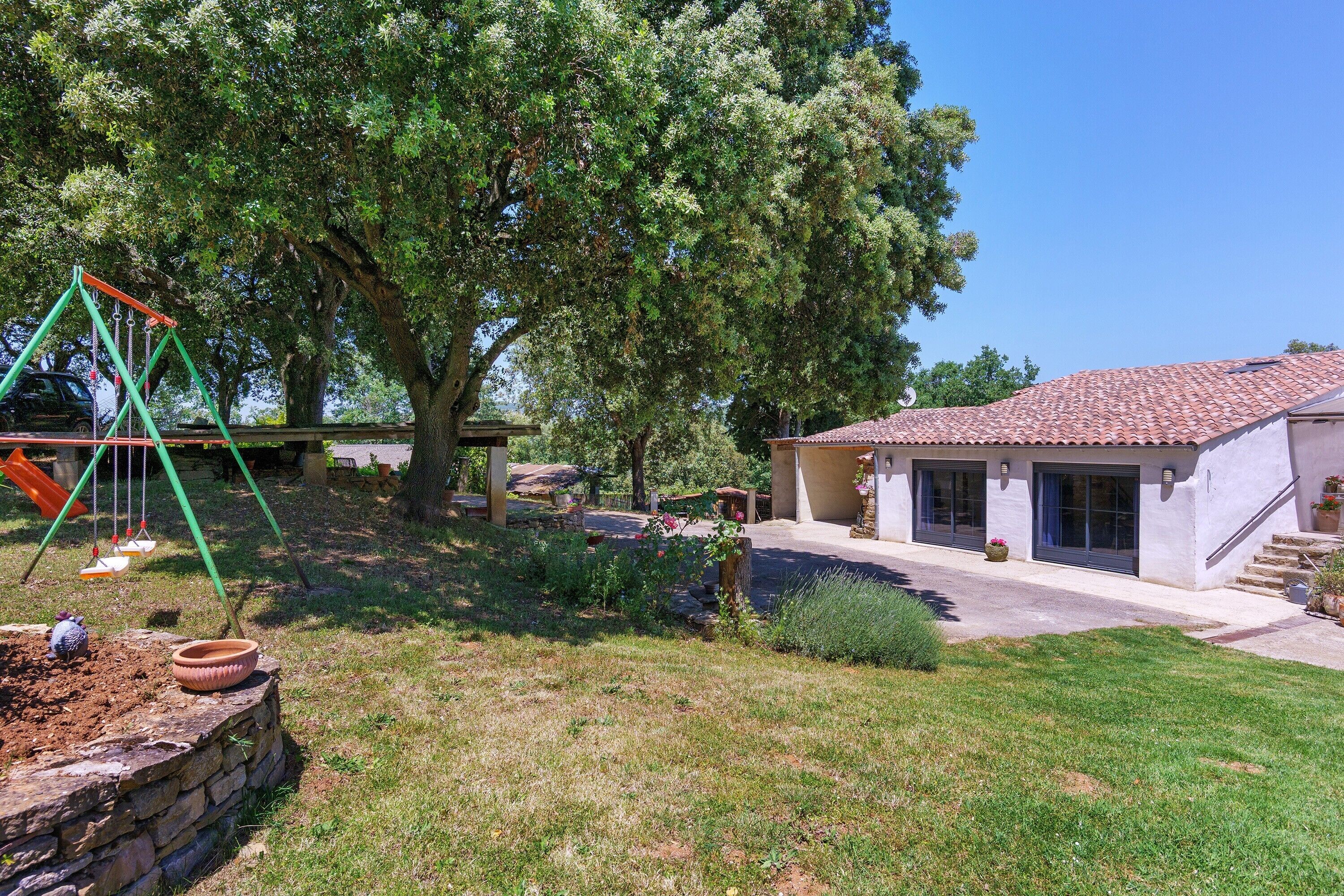A residential property with a patio, a swing set, and a large tree.