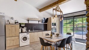 Una cocina moderna con comedor, electrodomésticos integrados y vistas amplias a través de grandes ventanales.