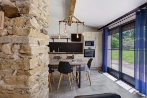 Eine moderne Küche mit Steinwand, Holztisch und -stühlen sowie einem großen Fenster mit Blick.