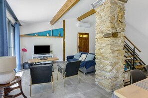 A living room with a stone wall, a television, a sofa, and a dining area.
