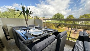 Een terras met een eettafel voor vier personen, omringd door rieten meubels.