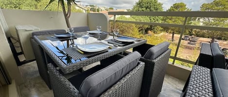 An outdoor dining area with a table set for four, surrounded by wicker furniture.