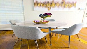 Un comedor con una mesa redonda, sillas tapizadas de gris y un centro de mesa decorativo.