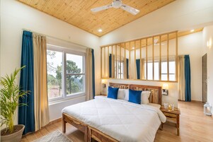 Un dormitorio con una cama grande, cabecera de madera, mesitas de noche, ventilador de techo y vistas al exterior.