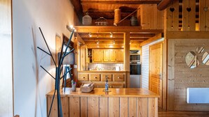 A wooden interior with a kitchen area, wooden beams, and a bar counter.
