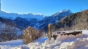 A snow-covered mountain landscape with a wooden bench and a metal railing in the foreground.