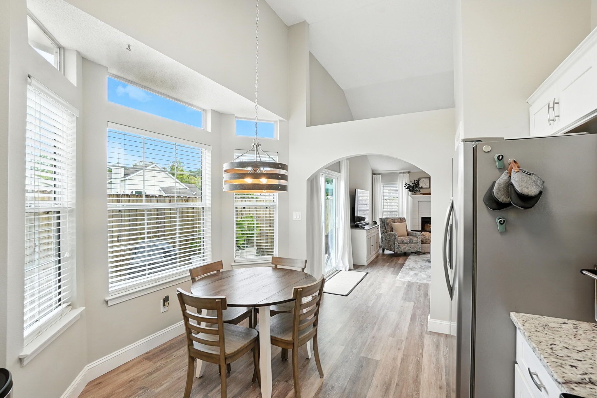 A spacious kitchen with a large island, a refrigerator, and a dining area with a wooden table and chairs.