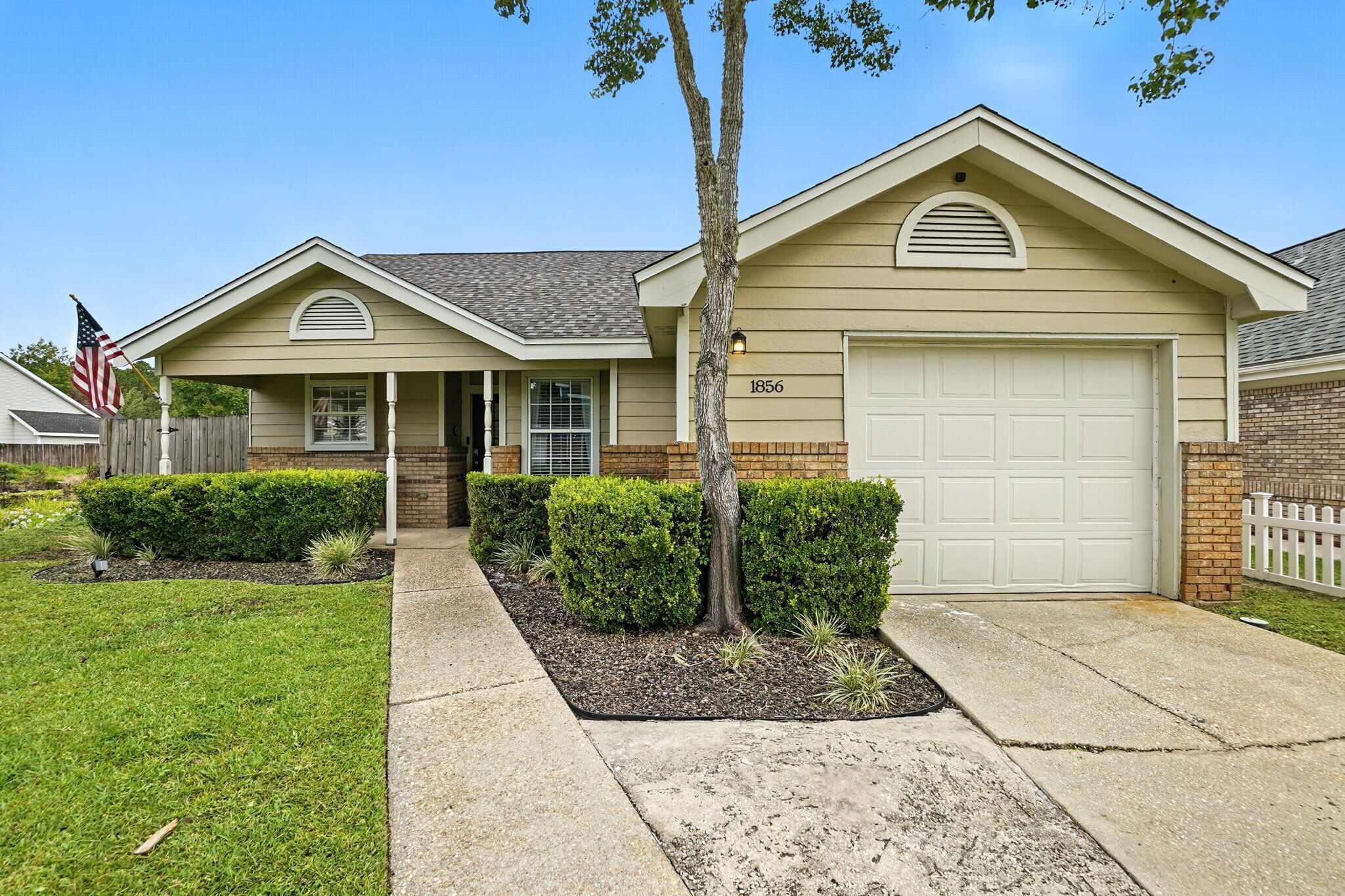 A single-story house with a garage, a front porch, and a well-maintained lawn.