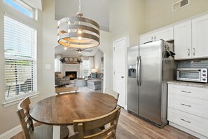 A modern kitchen with a central island, stainless steel appliances, and a dining area with a wooden table and chairs. - Sea Horse Cove: Fully Fenced, Kid and Pet Friendly (Fort Walton Beach)