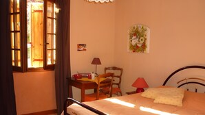 A bedroom with a bed, a desk, a chair, a lamp, and a window with curtains. - Near Sarlat in Périgord: Under the Linden Tree at Joelle and Guy’s – Country Room, Peace, Nature (Carsac-Aillac)