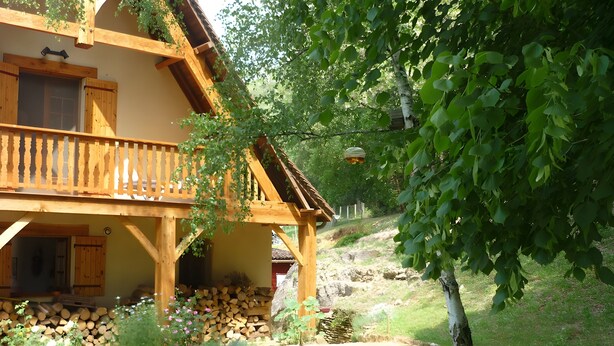 A wooden house with a balcony, a stone wall, and a tree in the foreground. - Near Sarlat in Périgord: Under the Linden Tree at Joelle and Guy’s – Country Room, Peace, Nature (Carsac-Aillac)