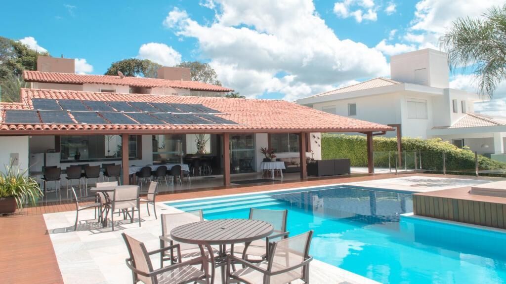 Una casa moderna con piscina, mobiliario exterior y paneles solares.