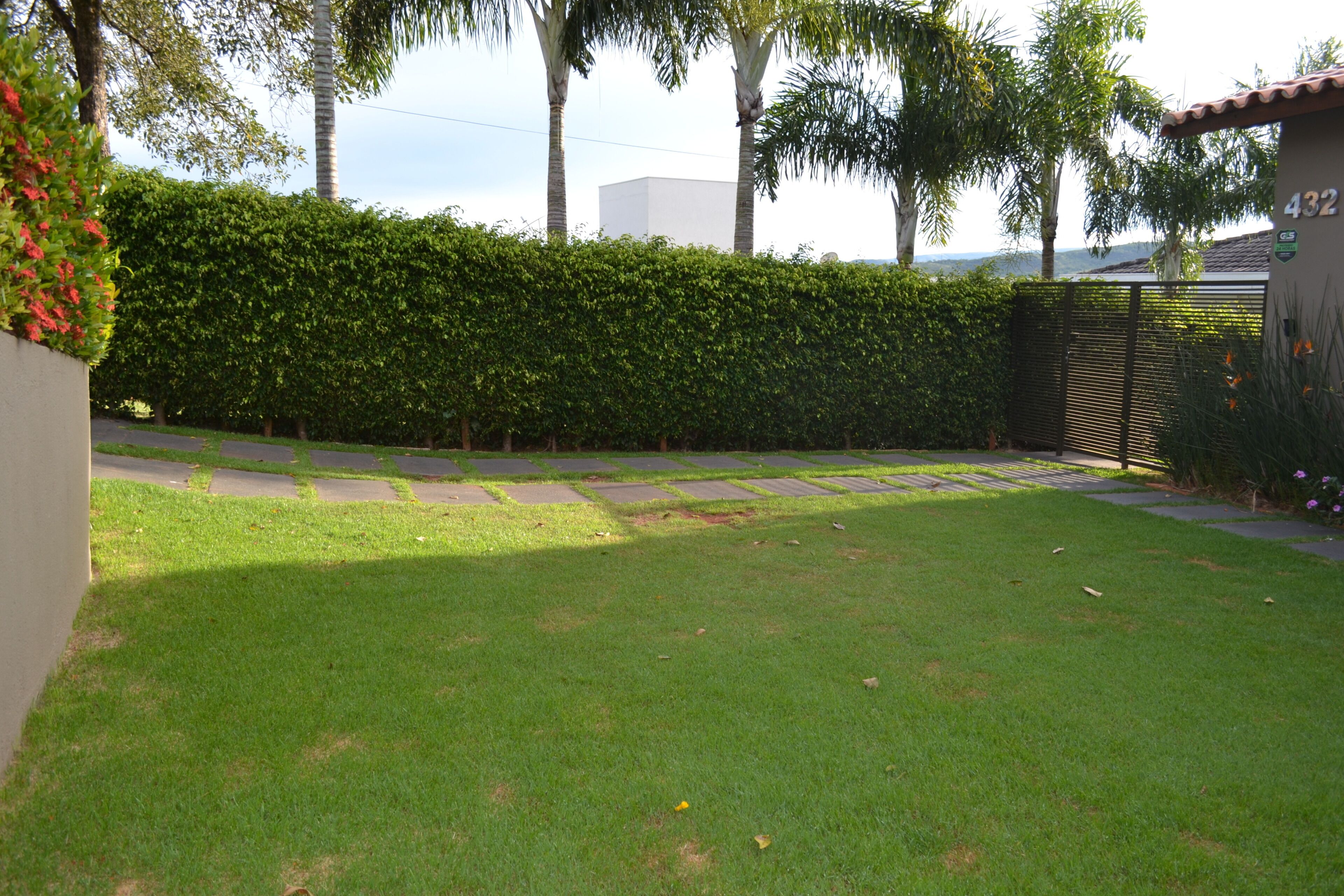 A well-maintained lawn, a hedge, and a building with the number 432.