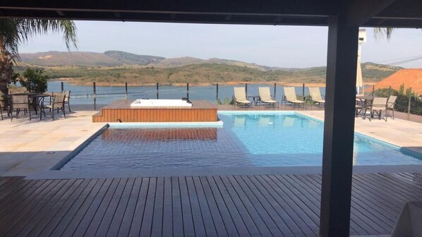 Una piscina al aire libre, sombrillas, sillones reclinables de piscina