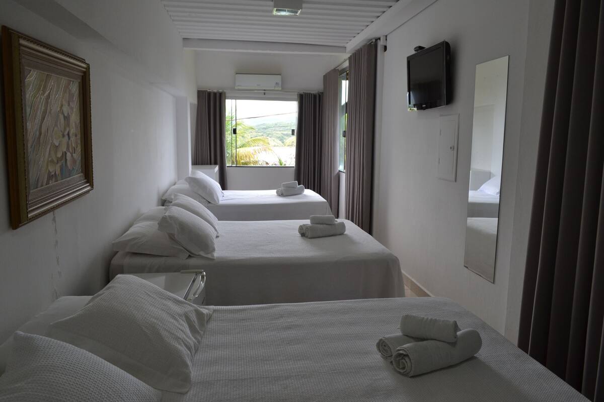 A hotel room with two beds, a television, a large mirror, and a painting on the wall.
