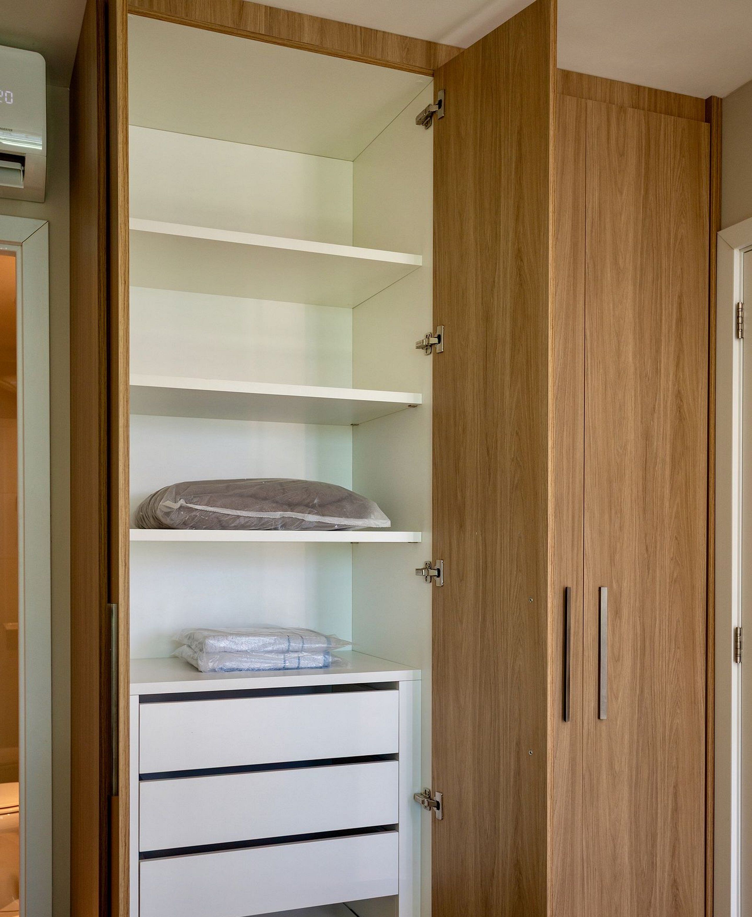 Ein Holzschrank mit mehreren Einlegeböden und Schubladen, einige Gegenstände sind in Folie verpackt.