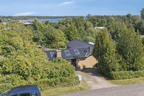 Een huis met schuin dak, omringd door dichte bomen en een heldere lucht.