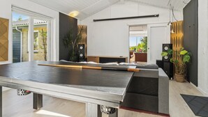 Een pooltafel in een kamer met een hoge plafond, een bed en uitzicht op buiten.