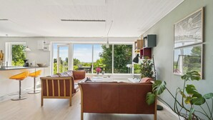 Een moderne woonkamer met een bank, een eettafel en een keukenhoek met een raam.