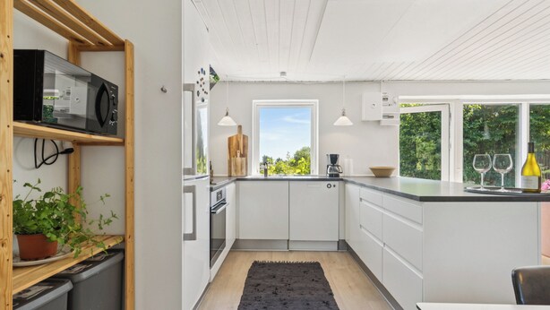 Een moderne keuken met witte kastjes, een zwart tapijt en een raam met uitzicht op groen.