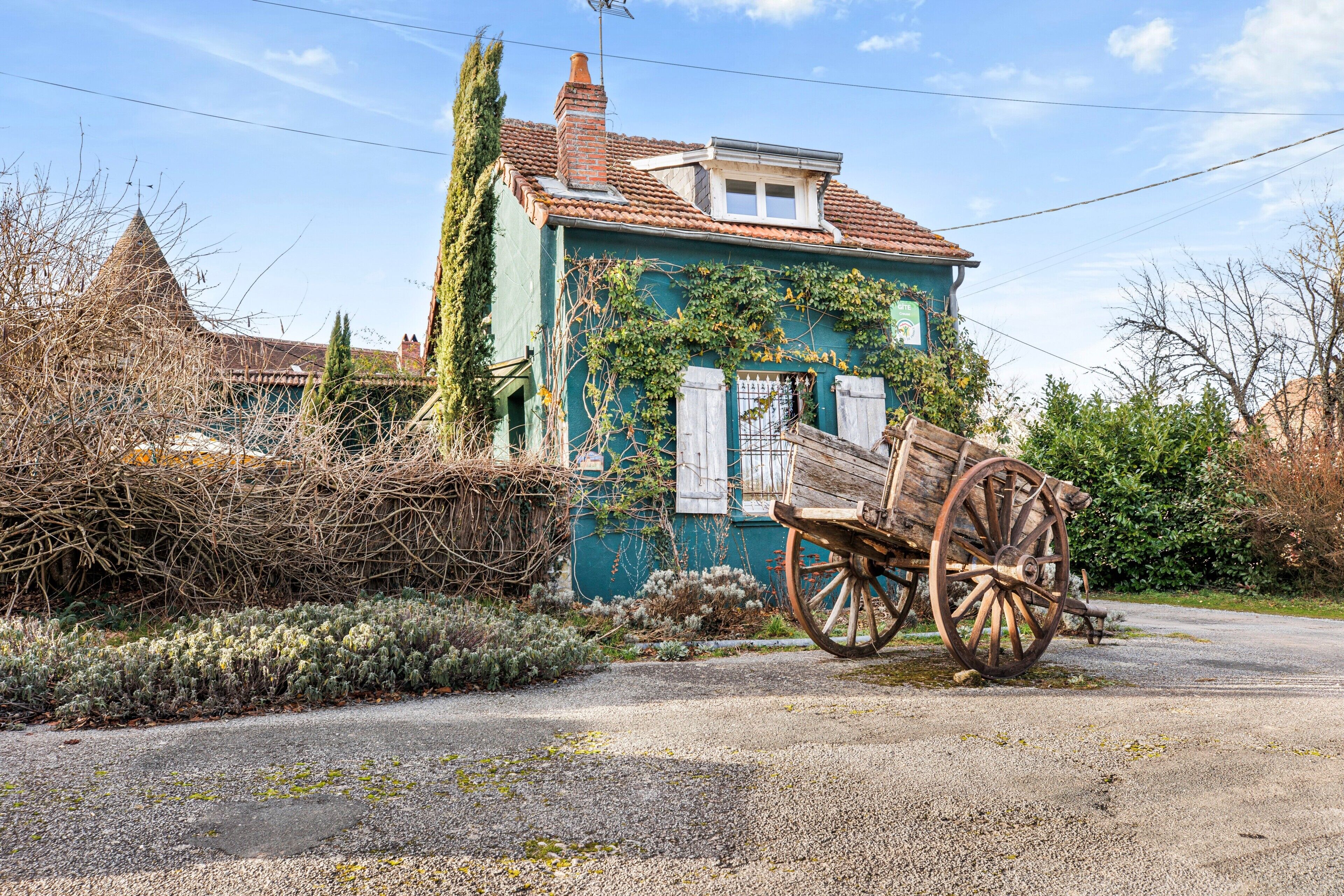 A house with a traditional design, a wooden cart, and a clear sky.
