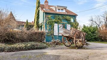 A house with a traditional design, a wooden cart, and a clear sky.