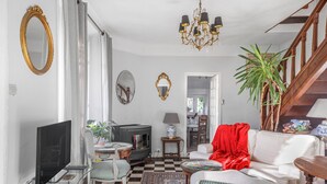 Un salon avec une télévision, un canapé, un fauteuil et un escalier.