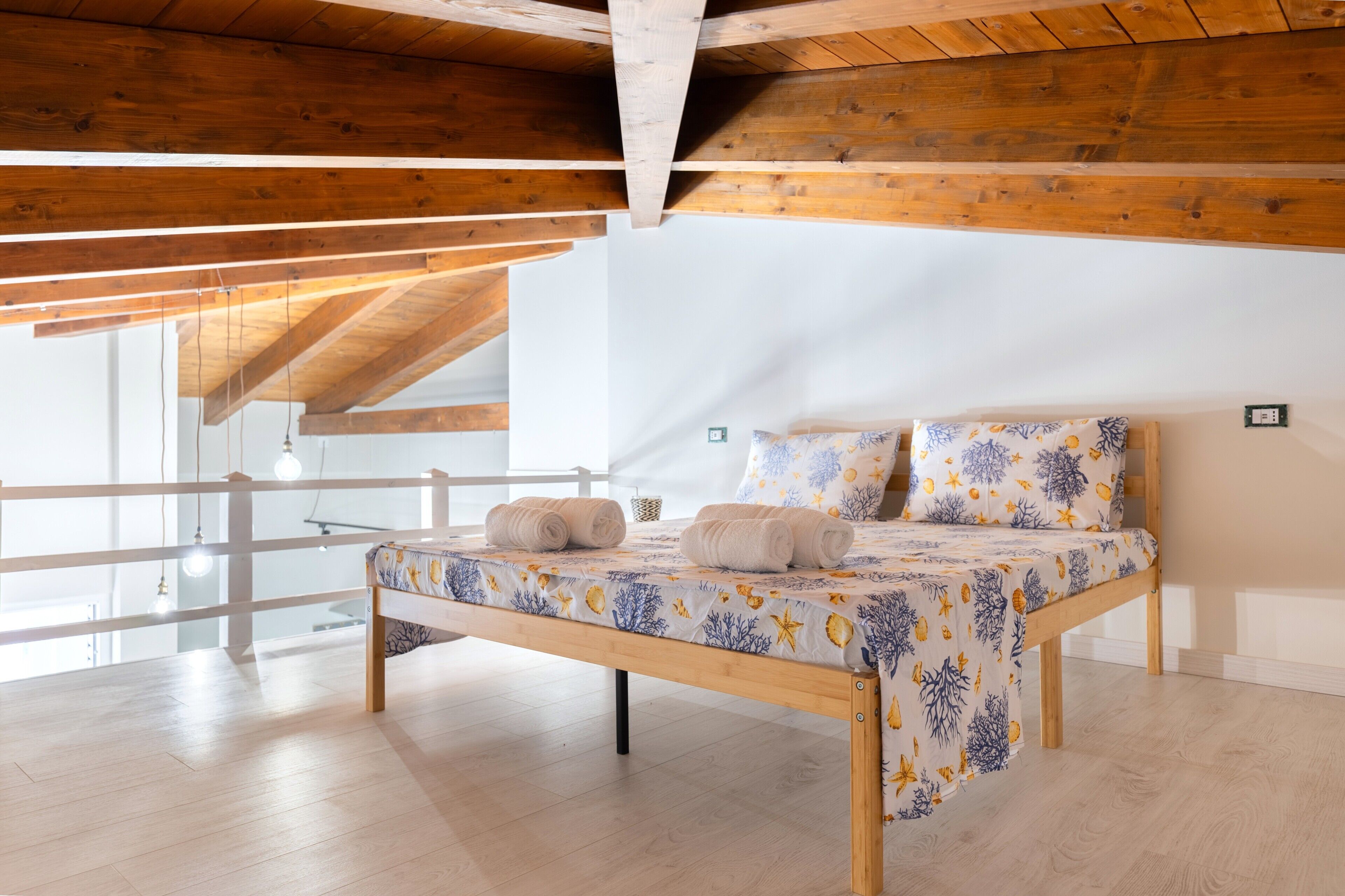 Une chambre à coucher avec un lit en bois, des murs blancs et un plafond en bois.