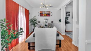 A dining area with a table set for two, a chandelier, and a painting on the wall. - Updated University Area Home with Hot Tub Near Charlotte Your Perfect Retreat! (Charlotte)